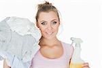 Portrait of smiling young woman with clothes and spray bottle over white background