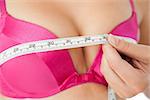 Extreme closeup of woman measuring chest in pink bra