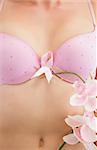 Closeup of woman with breast cancer awareness ribbon attached to bra and flower