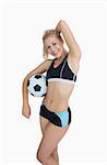 Portrait of happy woman in sportswear with football posing over white background