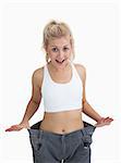 Young thin woman wearing old pants after losing weight over white background