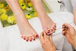 Closeup of woman polishing toe nails at spa center