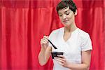 Young woman mixing hair color over red backdrop