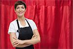 Portrait of a hairdresser with arms crossed against red curtain