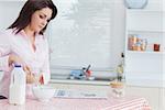 Young woman pouring cereal in bowl at kitchen worktop