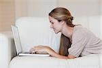 Side view of casual young woman using laptop on sofa