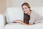 Portrait of casual young woman using laptop on sofa