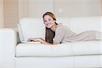 Portrait of casual young woman using laptop on sofa at home