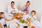 Family smiling around a roast dinner on the table