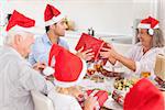 Happy family exchanging gifts at christmas time around the dinner table