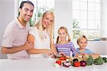 Smiling family cutting vegetables together in the kitchen