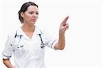 Portrait of female nurse pointing at invisible screen against white background