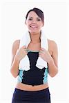 Portrait of happy woman in sportswear holding towel around neck over white background