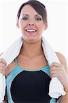 Portrait of young woman in sportswear holding towel around neck over white background