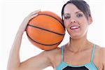 Portrait of happy woman in sportswear holding basketball on shoulder over white background