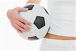 Midsection of fit woman in sportswear with football standing over white background