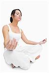 Young woman sitting in lotus position over white background