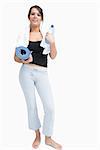 Portrait of young woman in sportswear holding water bottle and mat over white background