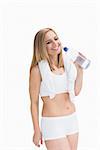 Happy young woman with towel around neck holding water bottle over white background