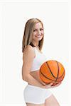 Portrait of happy woman in sportswear holding basketball over white background