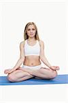 Portrait of young woman sitting in lotus position over white background