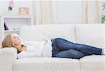 Casual thoughtful young woman lying on sofa at home