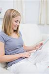 Casual happy young woman using digital tablet in living room at home