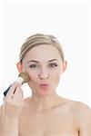 Portrait of young woman putting on makeup over white background