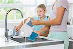 Daughter helping mother do the washing up in the kitchen