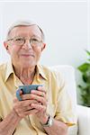 Elderly man looking at camera with a cup in the living room