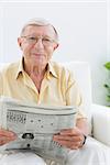 Smiling elderly man reading the news in the living room