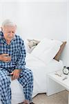 Old man suffering with belly pain in the bedroom