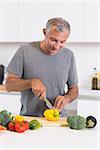 Cheerful man cutting a yellow pepper in the kitchen