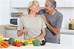 Smiling couple cutting vegetables together in the kitchen