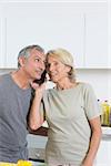 Mature couple listening a call together in the kitchen