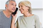 Happy mature couple listening a call together in the kitchen