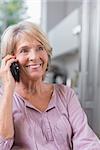 Smiling mature woman calling in the kitchen