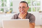 Smiling man at laptop in kitchen