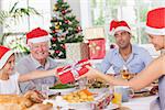 Mother giving daughter christmas present at christmas dinner