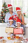 Family wearing santa hats holding christmas presents