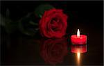 Romantic candle with red rose on black background