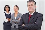 Businessman and his team standing with crossed arms in office