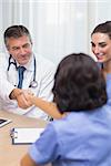 Smiling doctor shaking nurses hand during meeting