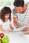 Dad and daughter reading a newspaper in kitchen