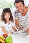 Dad and daughter reading a newspaper during breakfast in kitchen