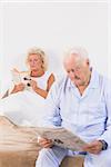 Elderly couple reading on the bed in the bedroom