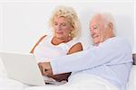 Aged couple using a laptop on the bed