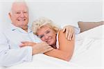 Cheerful couple lying on the bed and embracing