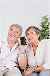 Old lovers listening to a smartphone looking camera