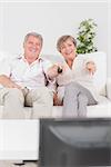 Old couple watching TV and pointing in sitting room